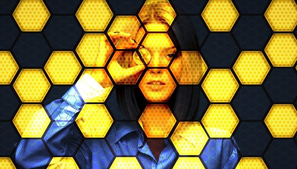 A pattern of hexagonal shapes in various shades of yellow, creating a honeycomb-like texture with a blurred central area.